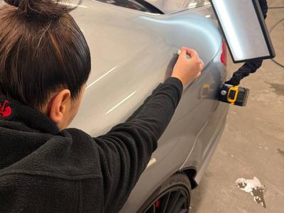 Beulendoktor bei der Dellenentfernung mit Reflektorleuchte